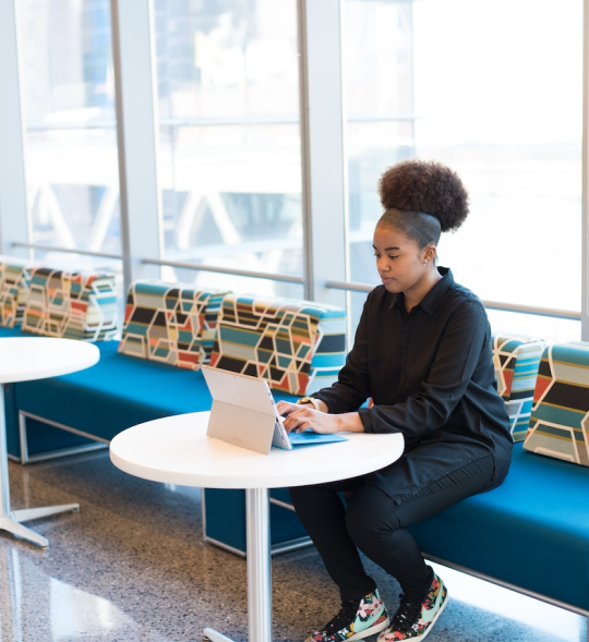 African american woman with phone laptop cafe